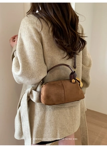 Detail showing oversized golden hardware and brown suede texture on a chic pillow bag