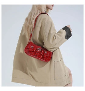 Close-up of red crocodile-patterned shoulder bag with silver buckles and Y2K punk rivets