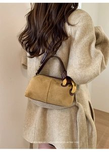 Detail of vintage suede cylindrical handbag with brown leather strap and gold buckle