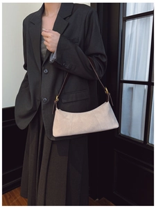 Detail of beige suede underarm bag showing dark brown strap and golden metal buckle