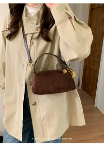 Detail of dark brown suede Boston bag with gold metal buckle and leather handle
