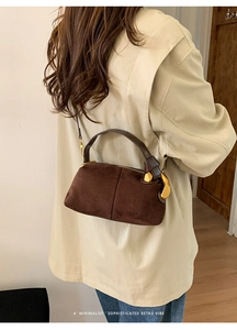 Detail of dark coffee suede Boston bag with artistic gold metal hardware on the side