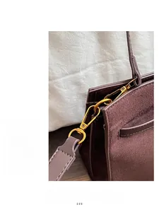 Détail de la ferrure dorée sur un grand sac cabas en daim marron pour femme