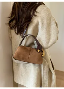 Brown suede pillow bag featuring large gold ring hardware shown on a model