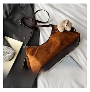 Détail d'un sac à main en daim marron avec pendentif chiot peluche et sangles en cuir