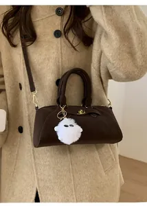 Dettaglio della borsa bowling in camoscio marrone scuro con ciondolo in peluche bianco