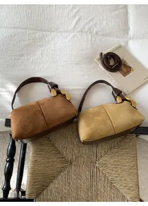 Detail of suede and leather pillow bags featuring iconic gold ring metal buckles