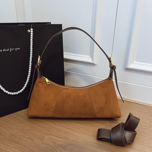 Detail of brown suede hobo bag with gold hardware and removable shoulder strap