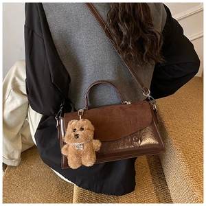 Detail der dunkelbraunen Tasche mit Plüschhund-Anhänger und Materialmix-Textur