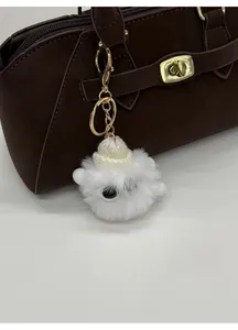 Dettaglio del charm mostro di peluche bianco con cappello su borsa in pelle marrone