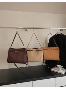 Trois cabas en daim marron, beige et jaune avec fermoir doré tournant sur des cintres