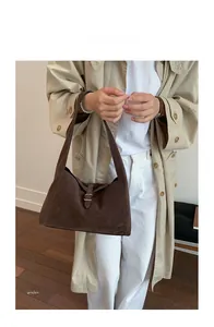 Detailed view of a brown suede shoulder bag with a silver buckle in a vintage French style