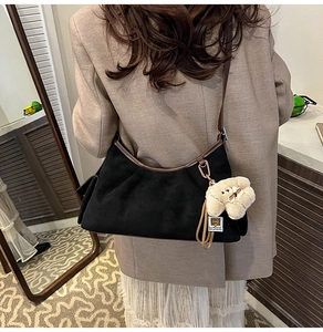 Détail du sac hobo noir mat avec garniture en cuir marron et breloque chien en peluche