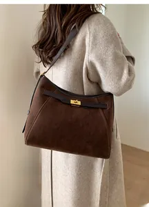Dettaglio della borsa tote in pelle scamosciata marrone con chiusura girevole dorata e manici