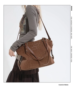 Detail of a large leopard print suede tote bag with bronze metal rings and adjustable strap