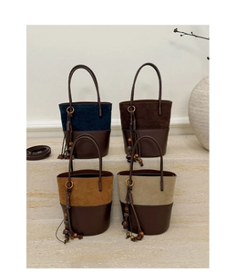 Detail of four bucket bags with mixed suede and leather texture on a stone step