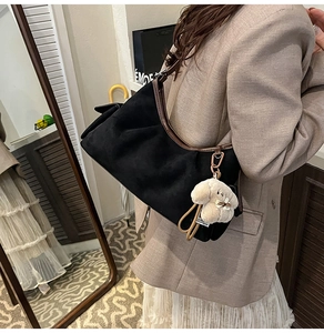 Détail du sac demi-lune en daim noir avec un adorable pendentif chien en peluche