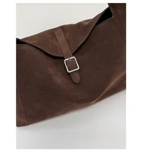 Detail of dark brown suede shoulder bag featuring high-quality silver buckle and strap
