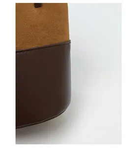 Detail of contrast stitching between brown suede and coffee leather material on bucket bag