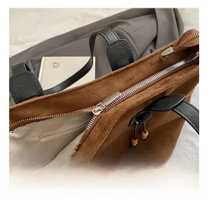 Dettaglio della cerniera in metallo e delle cuciture su una borsa tote in pelle scamosciata