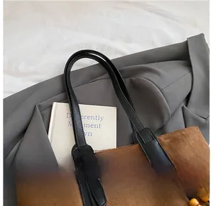 Dettaglio della borsa tote in pelle scamosciata marrone con manici neri e perline