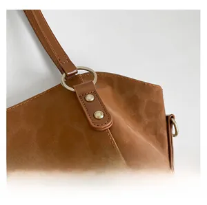 Detail of brown leather tote bag showing gold metal ring connector and reinforced rivets