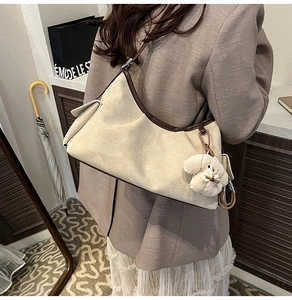 Detail der beigen Wildleder-Schultertasche mit braunem Lederbesatz und Plüschhund