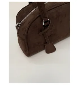Detail of dark brown suede boston bag featuring silver zipper and matte leather texture