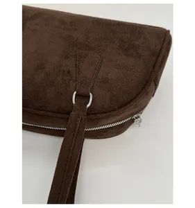 Detail of dark brown suede shoulder bag showing silver hardware and premium stitching