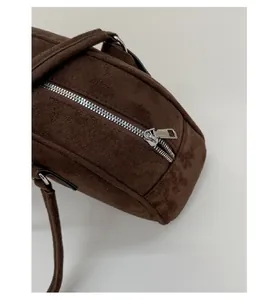 Detailed close-up of smooth silver metal zipper on dark brown suede bowling bag