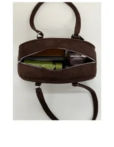 Top view of spacious brown suede bowling bag interior with daily essentials and silver zipper