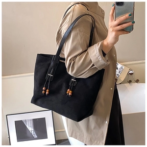Dettaglio della borsa tote in pelle scamosciata nera con coulisse e perline di legno