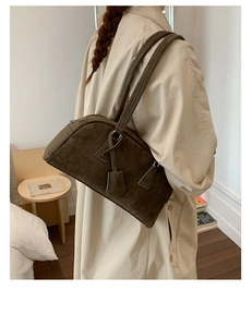Detail of dark olive suede pillow bag with dual handles and metal zipper closure