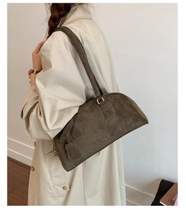 Detail of dark brown suede shoulder bag with thin straps on beige trench coat