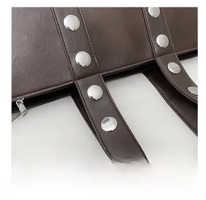 Detailed macro of dark brown leather tote with large silver rivets and stitching