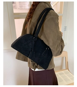 Detail view of the black suede minimalist shoulder bag texture and leather hangtag
