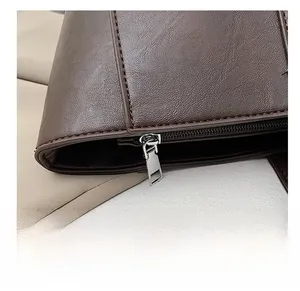 Close-up of smooth silver zipper and textured dark brown leather on the tote bag