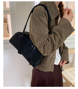 Side view of black suede bowling bag with slim strap shown on shoulder for daily wear
