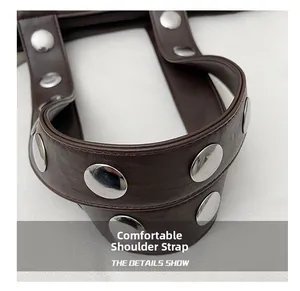 Close-up of brown leather shoulder strap with silver rivets for minimalist handbag