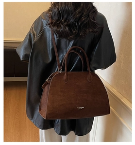 Detail of a large brown suede tote bag with silver branding and adjustable strap
