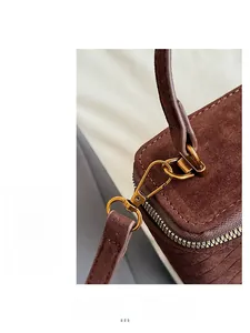 Macro detail of high-quality gold hardware and woven texture on a brown suede mini box bag