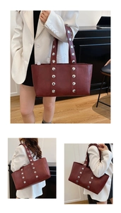 Close-up of silver metal studs and leather texture on a deep red minimalist tote bag