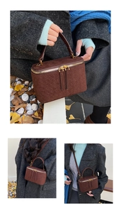 Detail of dark brown suede crossbody bag with woven texture and gold double zippers