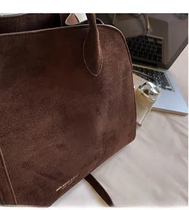 Detail shot of brown suede tote bag featuring side texture and logo engraving
