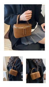 Detail of brown suede vanity bag with woven texture and gold zipper closure hardware