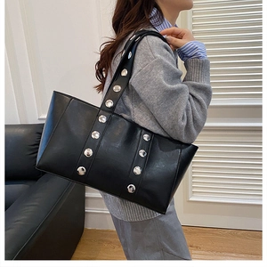 Détails des rivets argentés sur un sac cabas noir en similicuir porté par un mannequin