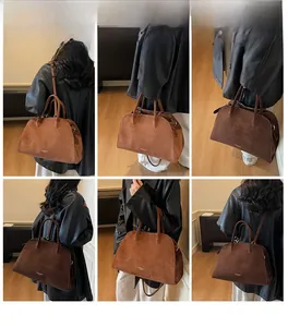 Detail view of large brown suede tote bag featuring cylindrical handles and leather texture