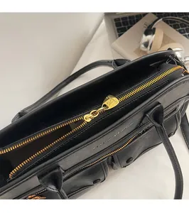 Detailed shot of smooth golden zipper and lychee texture on black leather tote bag
