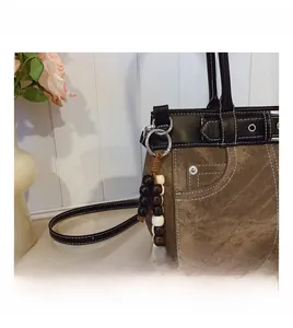 Detailed view of the retro stitching, denim texture, and beaded pendant on this shoulder bag