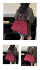 Macro view of burgundy suede tote bag featuring metallic brand logo and textured leather finish